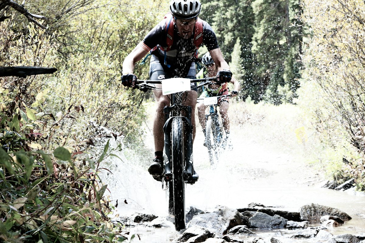 Mountain biker riding downhill trail through mountainous terrain